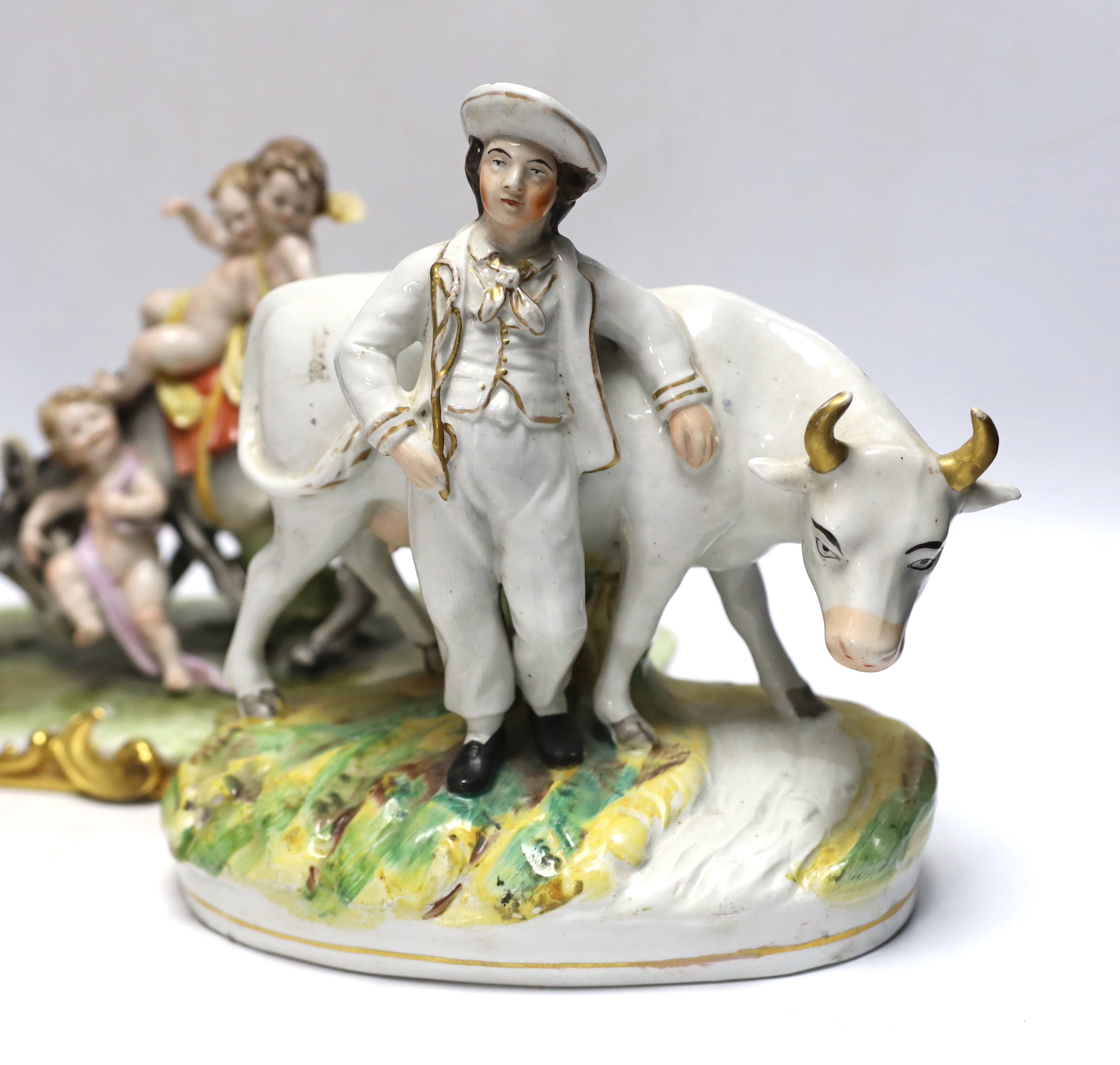 A pair of 19th century Staffordshire cow groups and an Italian donkey and cherub group, tallest 20.5cm
